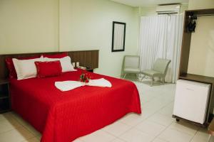 1 dormitorio con 1 cama roja y 2 toallas en Trindade Plaza Hotel, en Trindade