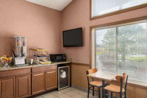 a kitchen with a table and a tv and a window at Days Inn by Wyndham Canastota Verona in Canastota