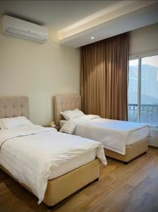 2 camas en una habitación de hotel con ventana en شاليه فخم مع مسبح وبحر خاص بالخبر en Half Moon Bay