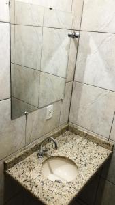 um balcão de casa de banho com um lavatório e um espelho em Hotel Ceolatto em Várzea Grande