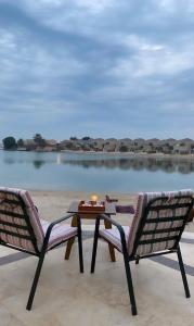 2 sillas y una mesa con una vela en el patio en شاليه فخم مع مسبح وبحر خاص بالخبر en Half Moon Bay