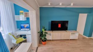 sala de estar con TV y escritorio con ordenador en Central Chic Otopeni - Self Check-in, Netflix, HBO MAX en Otopeni