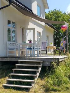 une maison avec 2 chaises et une terrasse couverte avec des escaliers dans l'établissement Gothem Viby Bed&Breakfast, à Slite
