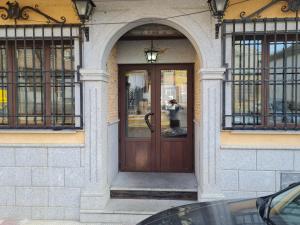 um edifício com uma porta de madeira com duas janelas em Hostal El Hidalgo em Villaluenga