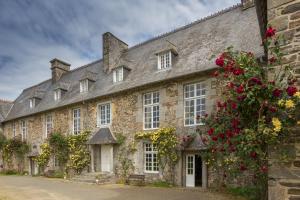 - un vieux bâtiment en pierre avec des fleurs rouges dans l'établissement Le Logis d'Equilly, à Équilly