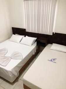 duas camas sentadas uma ao lado da outra num quarto em Hotel Ceolatto em Várzea Grande