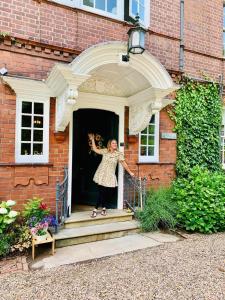 a woman standing on the front porch of a house at Hillthorpe Manor by Maison Parfaite - Large Country House with Hot Tub in Pontefract