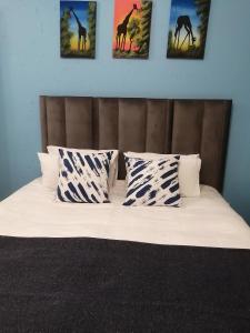 - un lit avec quatre oreillers et des photos de girafes dans l'établissement The Don Apt, Greenstone, à Edendale