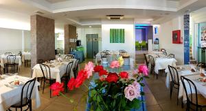 um restaurante com mesas e cadeiras com flores no meio em Hotel Sorriso - molto più di una stella em Riccione