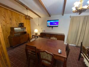 uma sala de jantar com uma mesa de madeira e uma televisão em CASA DE CAMPO POTRERILLOS em Potrerillos