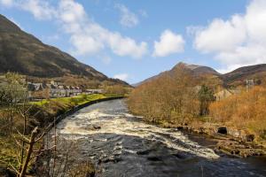 un fiume in una valle con montagne sullo sfondo di Unique restored Old Post Office a Kinlochleven