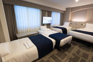 a hotel room with three beds and a flat screen tv at Hotel Rose Garden Shinjuku in Tokyo