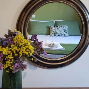 Olive Grove Cottage Skalani في Knossós: غرفة نوم مع مرآة وسرير مع الزهور