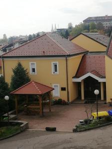 a yellow house with a red roof and a pavilion at Studio apartman Jordanovac Rebro in Zagreb