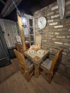 een tafel en stoelen met een klok op een bakstenen muur bij Au Bien-Etre D’Elise - Chambre d’hôte in Fayat