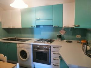 a kitchen with blue cabinets and a washing machine at Casa del Sole affacciato sul mare in Cervo