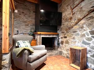 Casa Sinera في Roní: غرفة معيشة مع موقد حجري وكرسي
