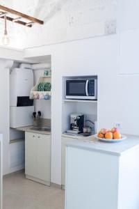 una cucina con armadi bianchi e un piatto di frutta su un bancone di Suite Dantè - Typical Apulian Rooms a Cisternino