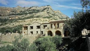 un edificio de piedra con una montaña en el fondo en Mas de la Vall del Frare, en Gandesa