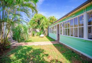 a green house with a yard with palm trees at La Garçonniere in Saint-Pierre