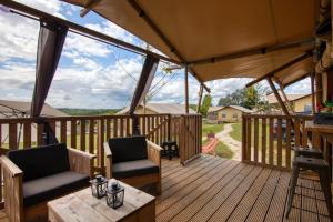 une terrasse en bois avec deux chaises et une table dans l'établissement JOINS! Glamping Aquitaine, à Saint-Aigne