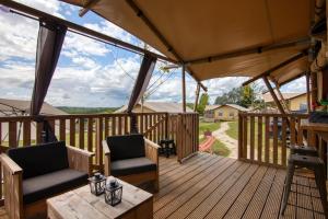 a wooden deck with two chairs and a table at JOINS! Glamping Aquitaine in Saint Agne