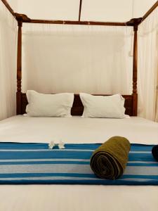 a bed with blue and white sheets and pillows on it at Twice Happy Beach Garden in Tangalle