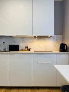 eine Küche mit weißen Arbeitsflächen und weißen Schränken in der Unterkunft Enes Apartments Legnicka Street A in Breslau