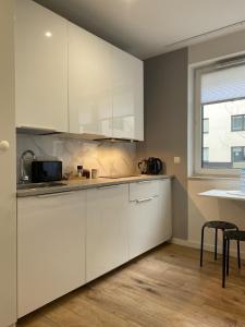 eine Küche mit weißen Schränken, einem Tisch und einem Fenster in der Unterkunft Enes Apartments Legnicka Street A in Breslau