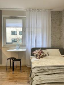 Schlafzimmer mit einem Bett, einem Tisch und einem Fenster in der Unterkunft Enes Apartments Legnicka Street A in Breslau
