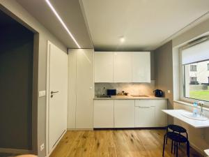 eine Küche mit weißen Schränken, einem Waschbecken und einem Fenster in der Unterkunft Enes Apartments Legnicka Street A in Breslau