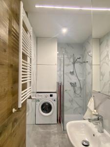 ein Badezimmer mit einer Waschmaschine und einem Waschbecken in der Unterkunft Enes Apartments Legnicka Street A in Breslau