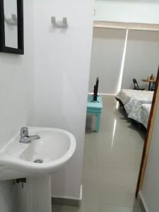 een witte badkamer met een wastafel en een bed bij APARTAESTUDIO EN MANGA CARTAGENA in Cartagena