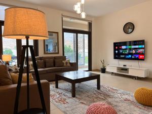 ONE 2BHK Elegant Apartment in Muscat Bay 03 في مسقط: غرفة معيشة مع أريكة وطاولة وتلفزيون
