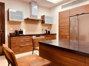 ONE 2BHK Elegant Apartment in Muscat Bay 03 في مسقط: مطبخ بدولاب خشبي وثلاجة