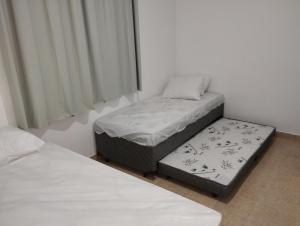 2 łóżka pojedyncze w pokoju z oknem w obiekcie PRAIA ENSEADA - WI-FI e AR CONDICIONADO w mieście Guarujá