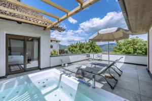 een hot tub op een patio met een parasol bij Hotel Ansitz Rungghof in Appiano sulla Strada del Vino