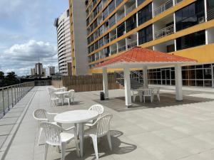 un patio con tavoli, sedie e ombrellone di MIX APART Hotel a Brasilia