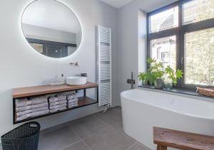 een badkamer met een wit bad en een spiegel bij B&B De Oude Dorpsslagerij in Nuth