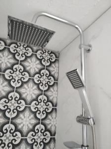a shower with a black and white patterned wall at Kadmilos suites Samothraki in Samothraki