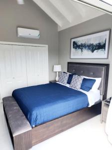 a bedroom with a large bed with a blue blanket at Brand New Luxurious Townhouse in Negril in Negril