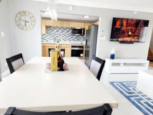 a dining room with a table and a clock on the wall at Brand New Luxurious Townhouse in Negril in Negril