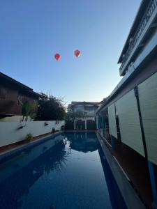 two kites flying over a swimming pool next to a building at Jasmine Vangvieng Hotel in Vang Vieng