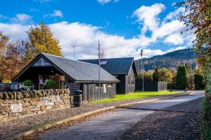 ein Gebäude mit einer Steinmauer neben einer Straße in der Unterkunft Mains of Taymouth Country Estate 5* Maxwell Villas in Kenmore