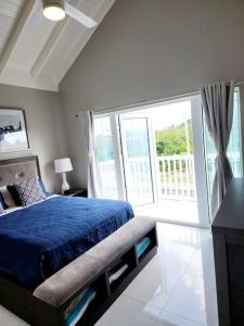 a bedroom with a blue bed and a large window at Brand New Luxurious Townhouse in Negril in Negril