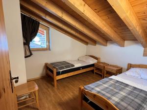 una camera con due letti e soffitti in legno di Pracondu 1 001 - OUTDOOR & FUN apartment 8 pers a Nendaz