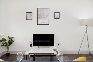 sala de estar con TV en una pared blanca en High spec 2 Bed apartment w/parking available, en Londres