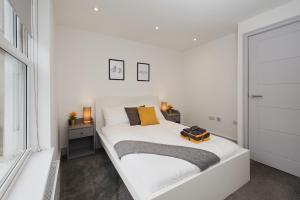um quarto branco com uma cama branca e uma janela em High spec 2 Bed apartment w/parking available em Londres
