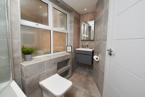 baño con aseo y lavabo y ventana en High spec 2 Bed apartment w/parking available, en Londres