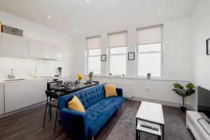 sala de estar con sofá azul y cocina en High spec 2 Bed apartment w/parking available en Londres